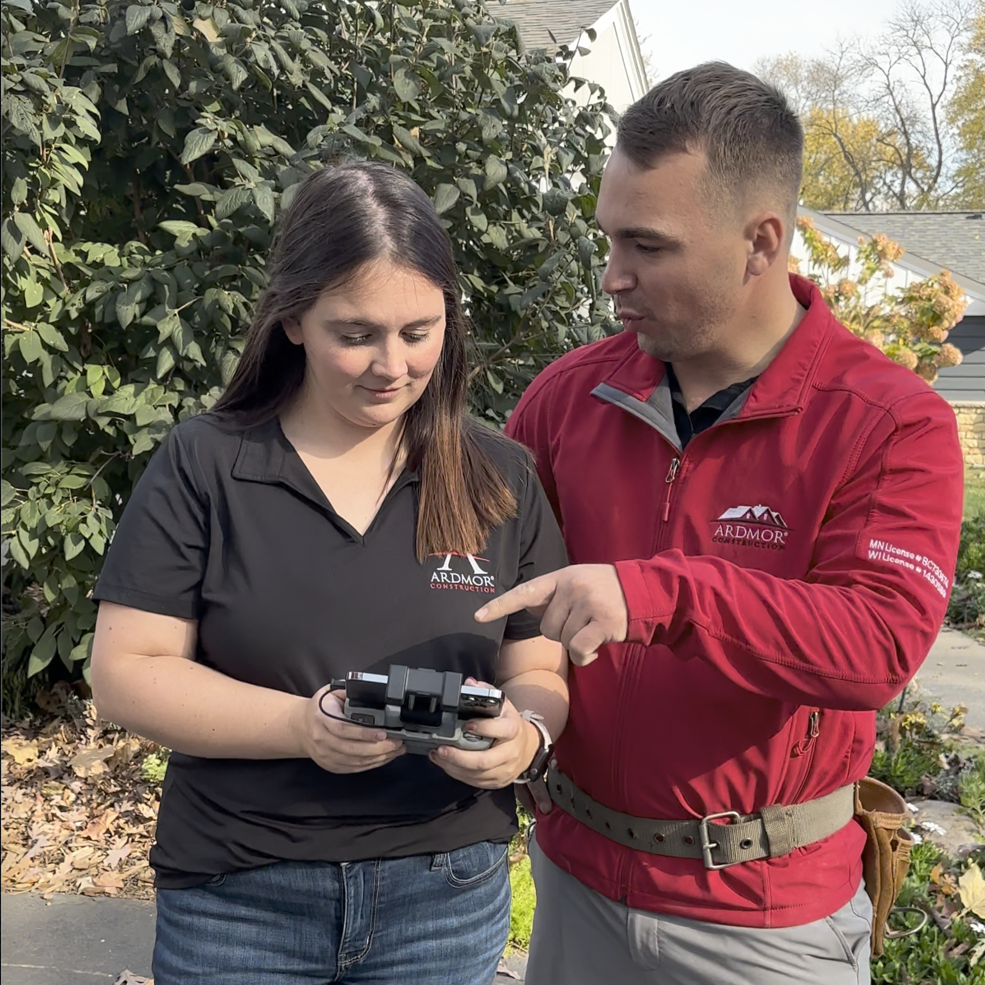 Picture of a male and female employee looking at the screen on a drone controller. 