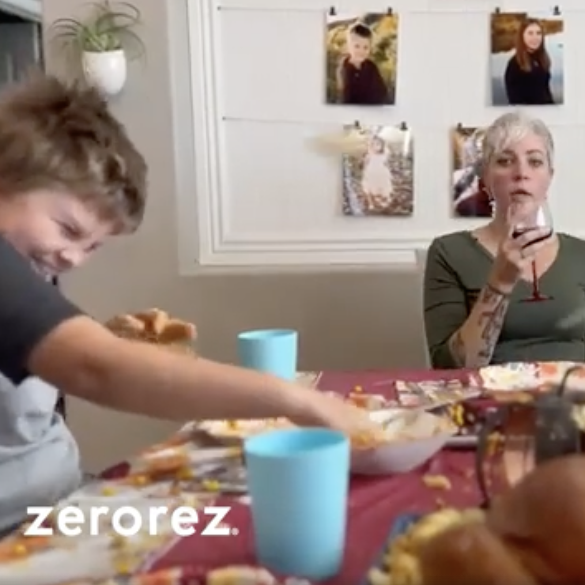 Woman sitting at a table drinking a glass of wine while kids throw food at each other. 