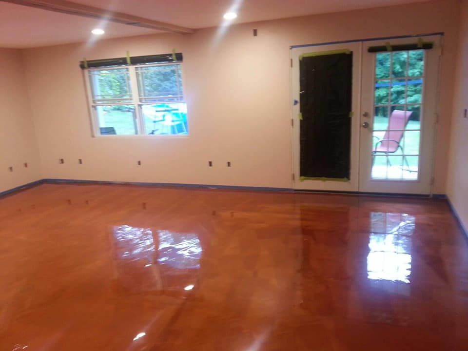 A room with a shiny, copper-colored epoxy floor; windows and a glass door let in natural light.