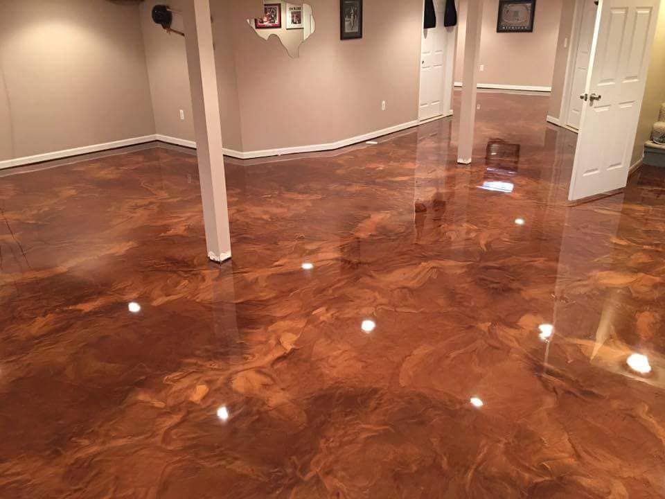 Shiny copper-colored epoxy flooring in a basement, with beige walls, support beams, and white doors.