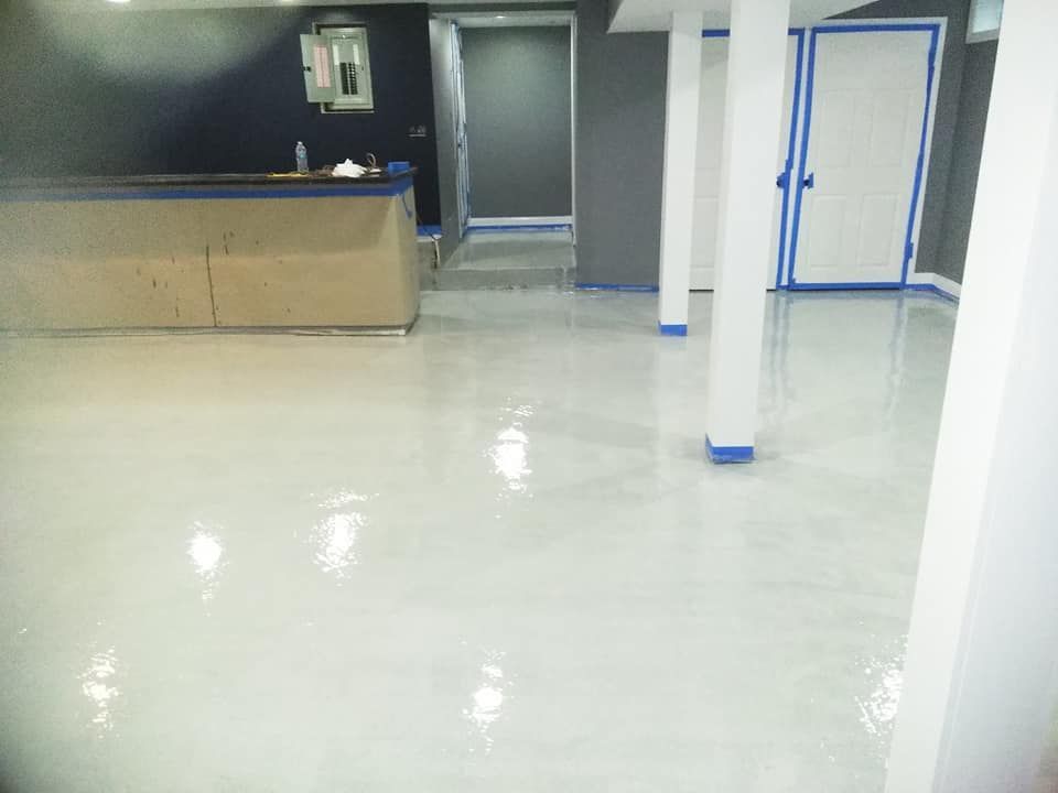 White epoxy floor in a room with a bar, columns, and doors. Blue painter's tape outlines the trim.