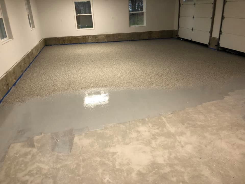 Garage floor partially coated with light gray epoxy. Finished section shows flecks.
