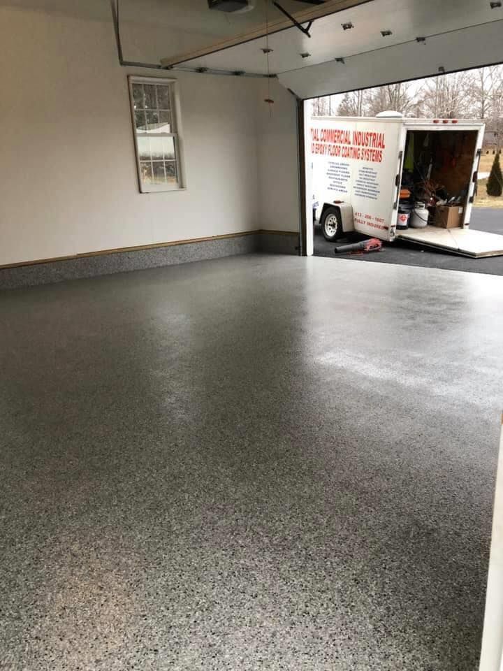 Garage with a gray epoxy floor. A trailer is parked inside the garage.
