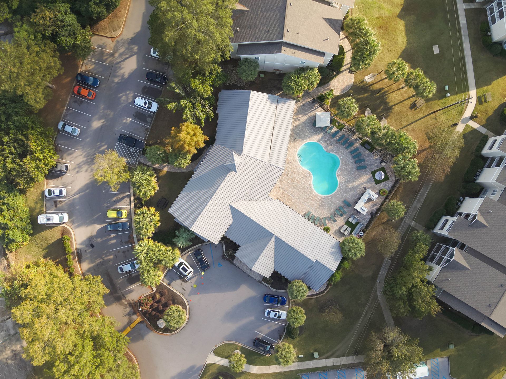 Aerial view of a town with buildings, trees, and roads, blue sky above.