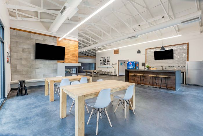 Modern break room with counter seating, soda dispensers, and a TV.