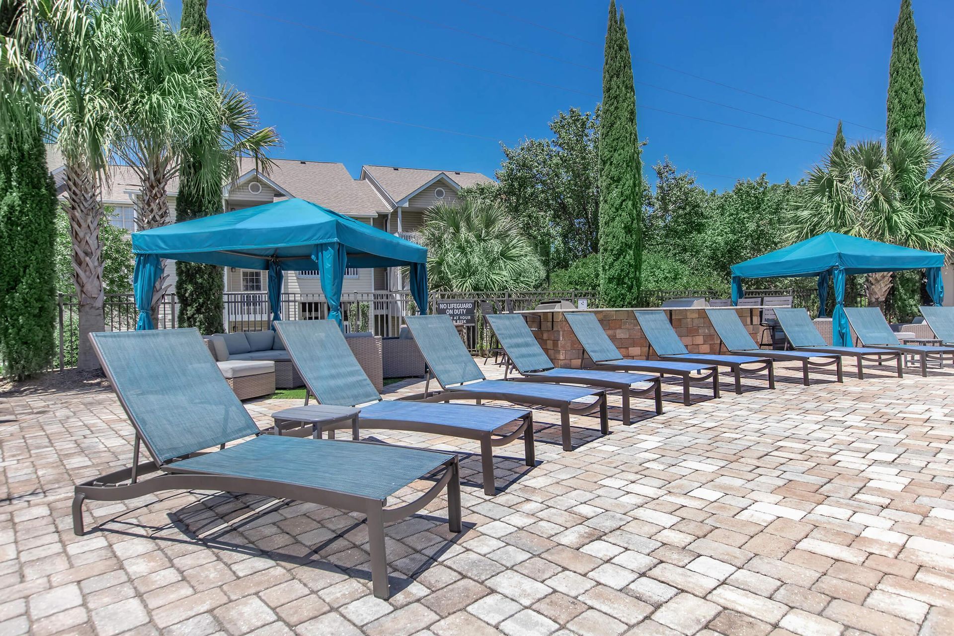 A row of lounge chairs and umbrellas are lined up next to a swimming pool at Rivers Edge at Carolina Stadium.