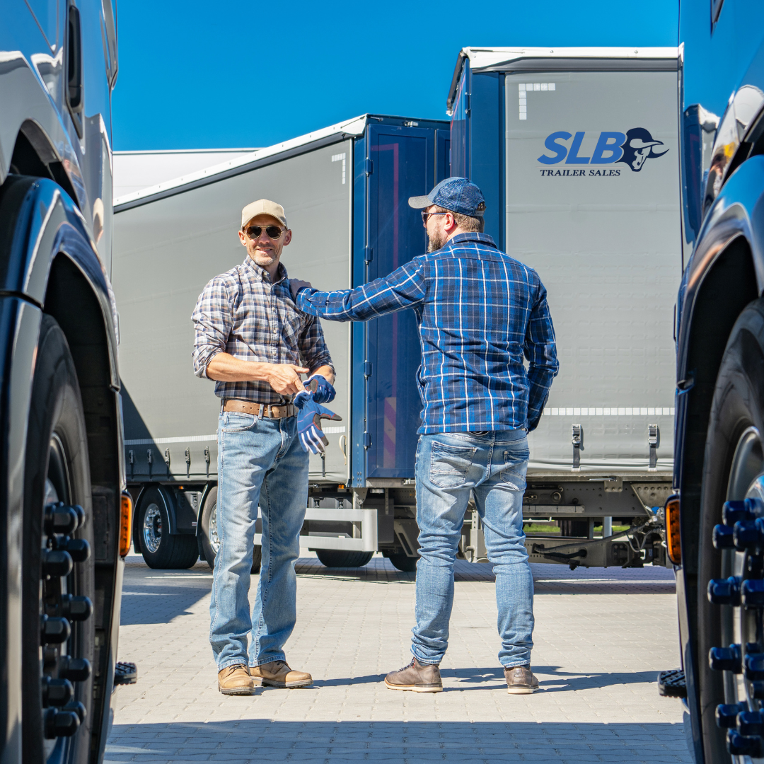 A man is standing in the back of a semi truck.
