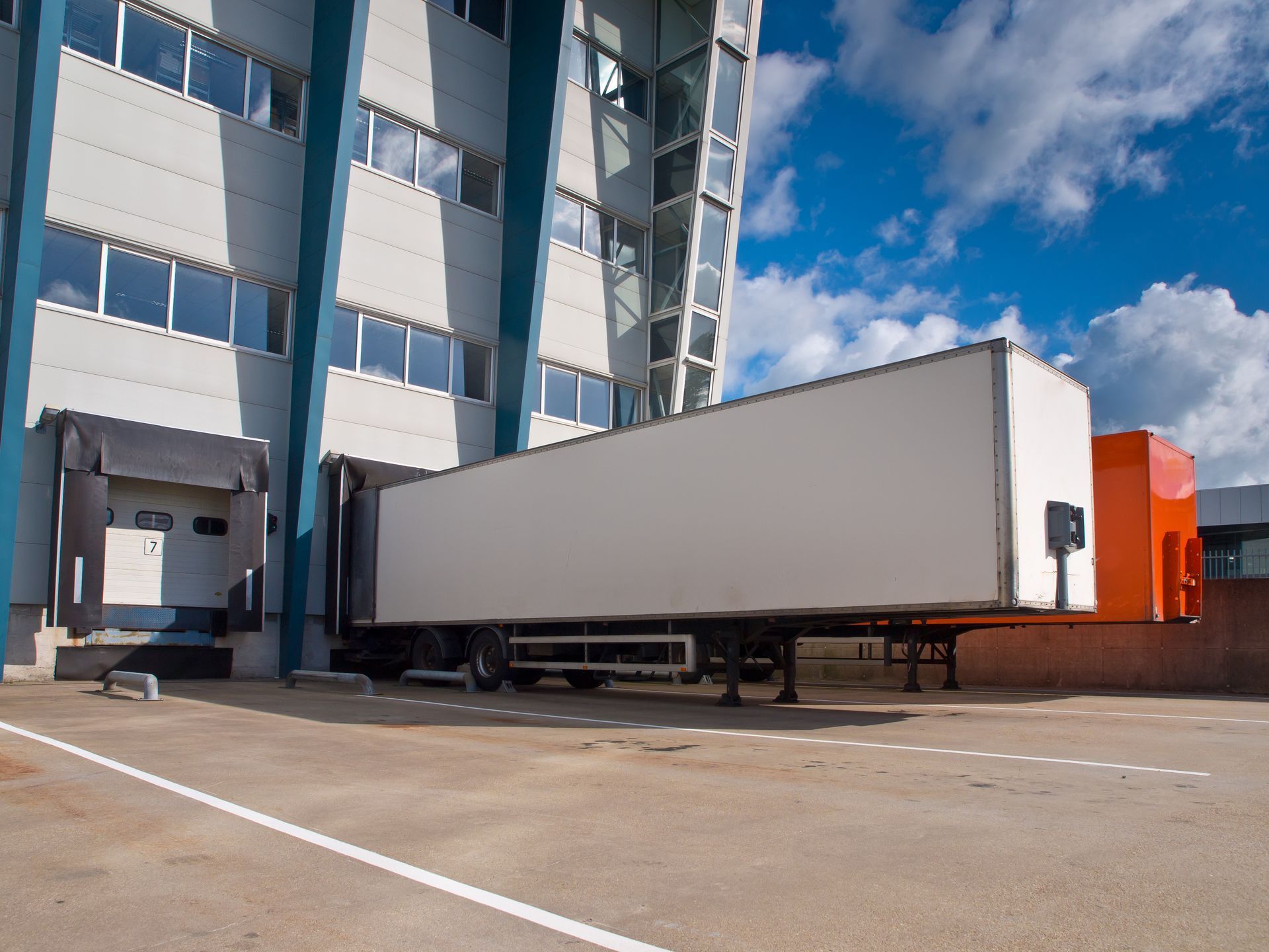 A white semi truck is parked in front of a building.
