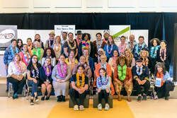 A large group of people smiling and posing for a photo on a stage in front of a banner.