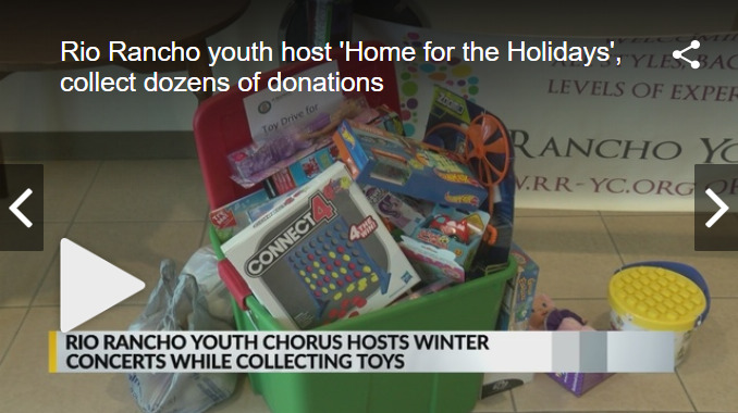 A green plastic bin filled with donated toys, including a Connect 4 game, sitting on a tiled floor.