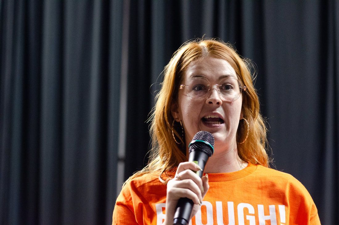 A person wearing an orange shirt with the word 