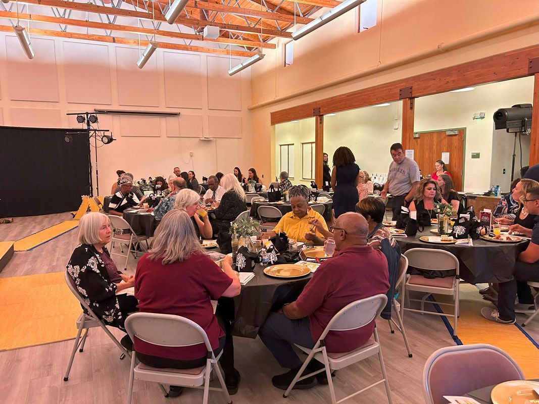 A group of people sitting at tables in a large hall during an indoor banquet or event.