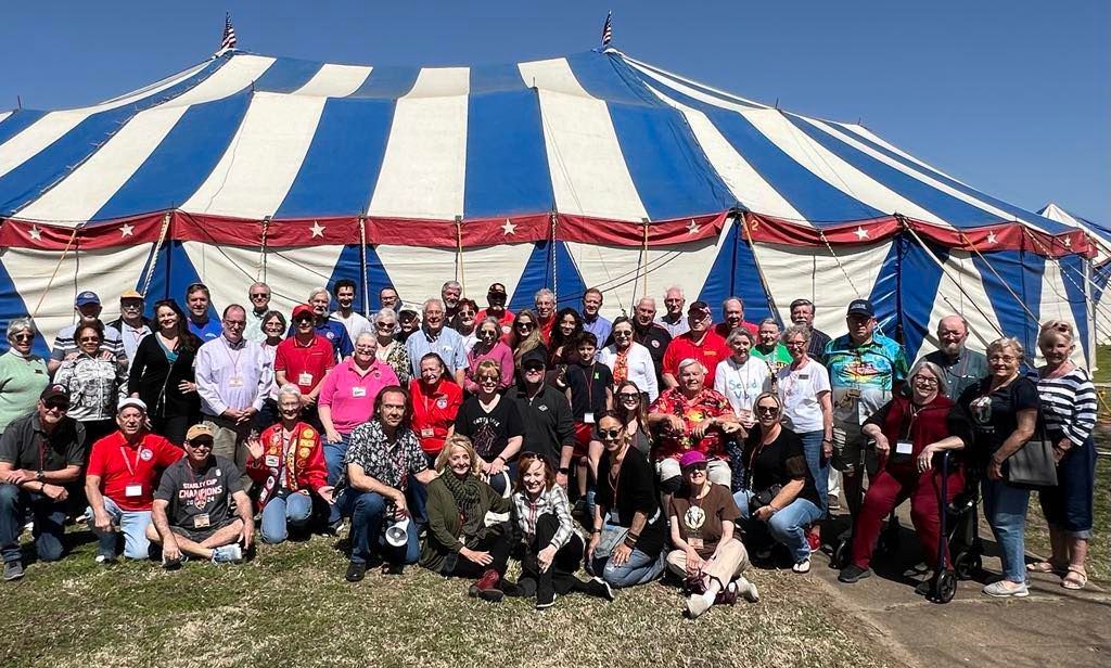 A large group of people are posing for a picture in front of a blue and white tent.
