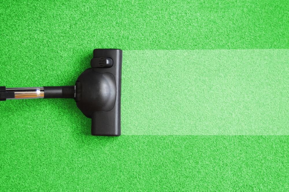A Vacuum Cleaner is Cleaning a Green Carpet — Great Lakes Carpet Cleaning & Restoration In Taree, NSW