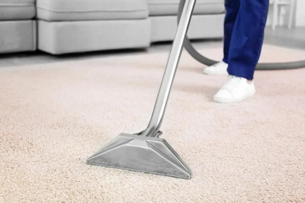 A Person is Using a Vacuum Cleaner to Clean a Carpet — Great Lakes Carpet Cleaning & Restoration In Hallidays Point, NSW