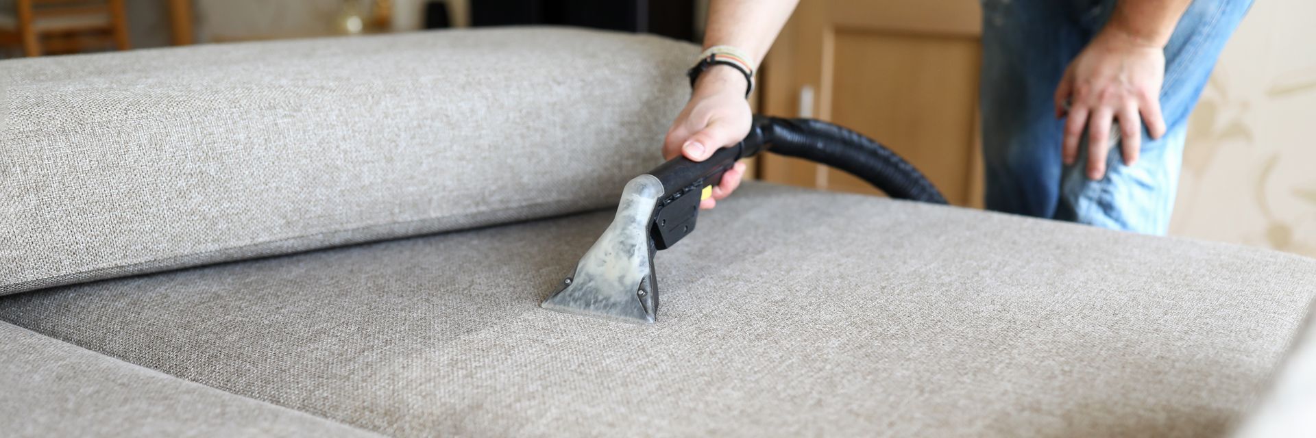 A Person is Cleaning a Couch With a Vacuum Cleaner — Great Lakes Carpet Cleaning & Restoration In Hallidays Point, NSW