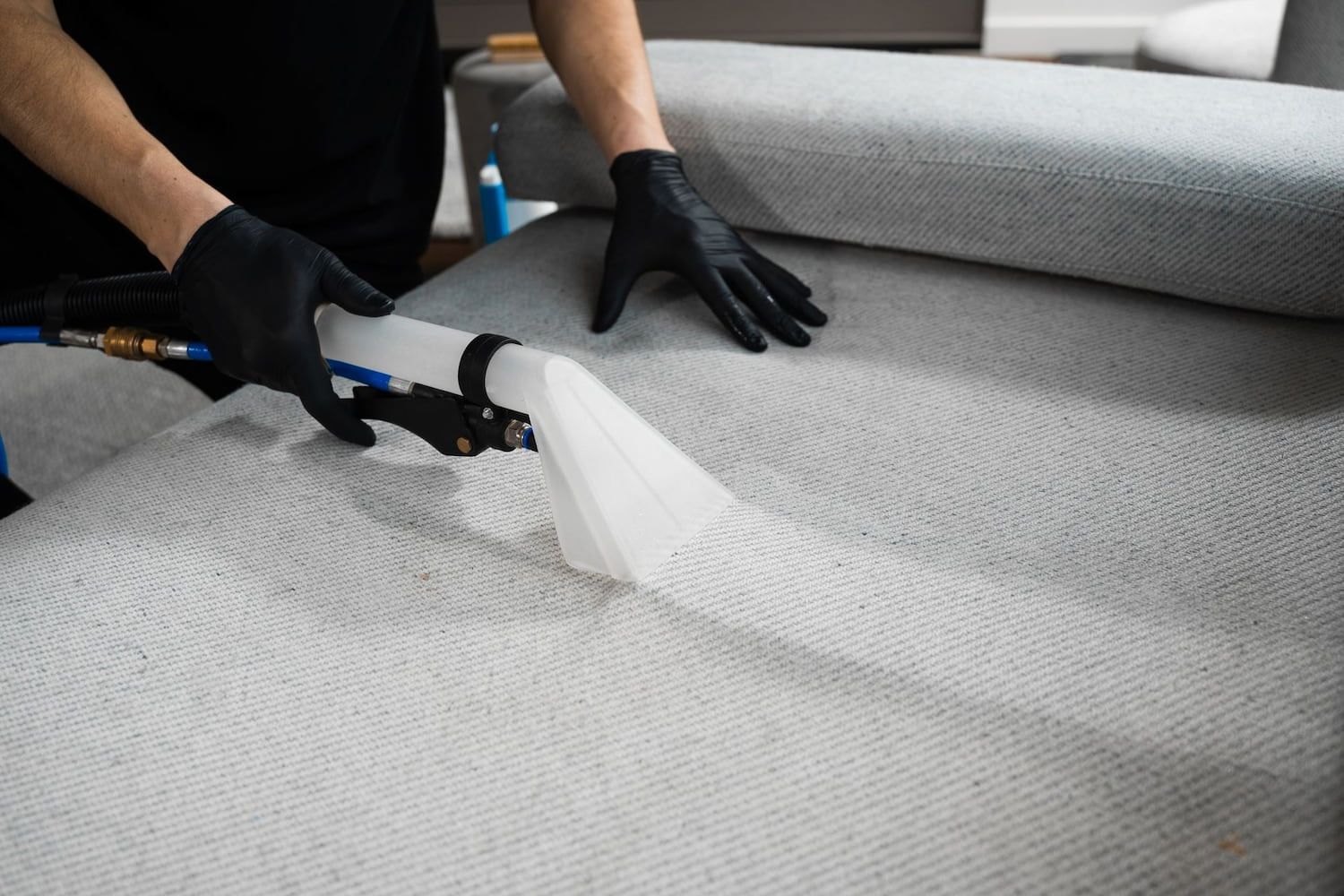 A Person is Cleaning a Couch With a Vacuum Cleaner — Great Lakes Carpet Cleaning & Restoration In Hallidays Point, NSW