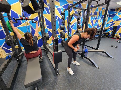 Client performing a strength exercise in the Royal Blue Fitness studio with coaching support during a small training session.