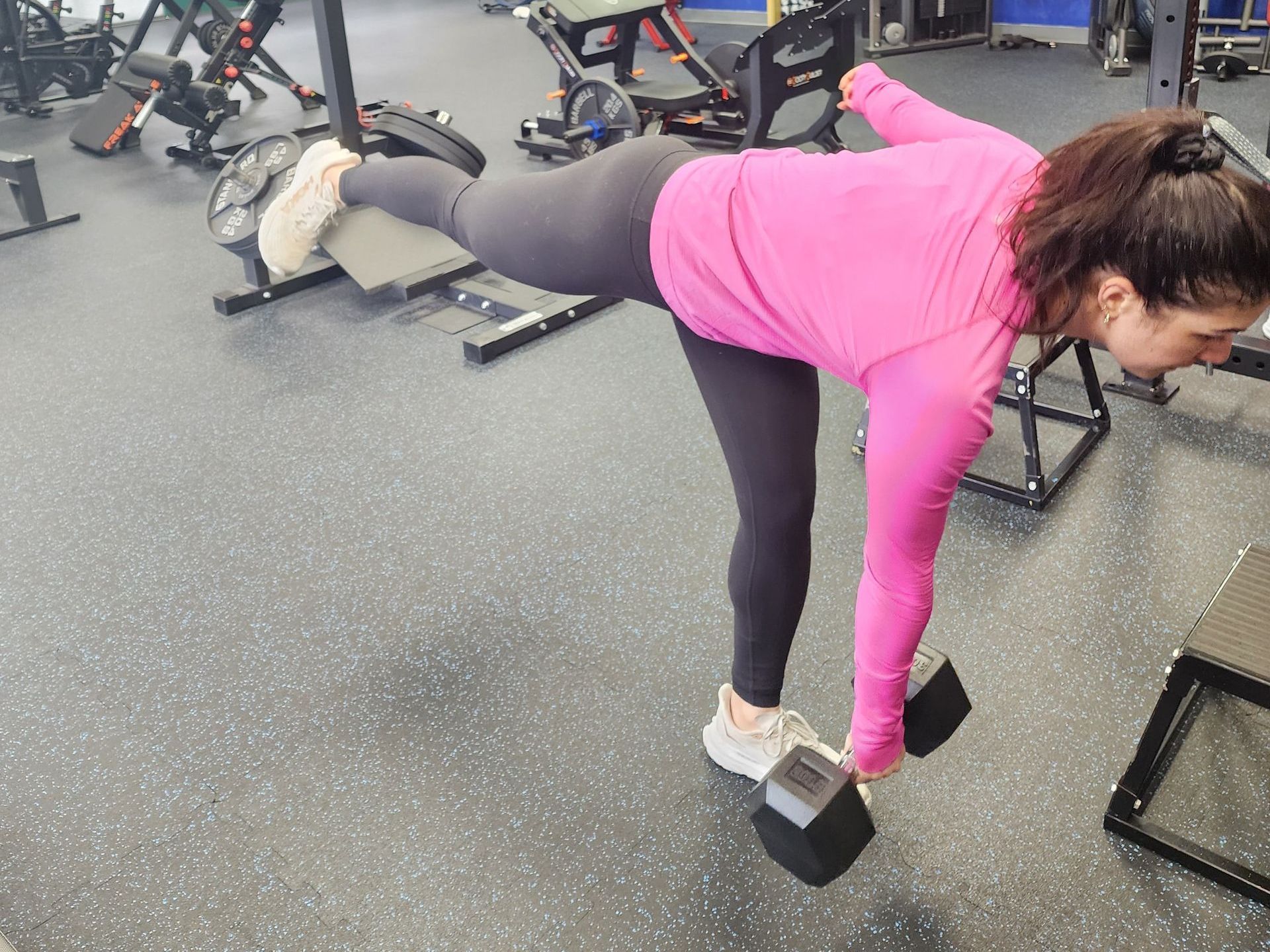 Young lady in gym attire performing a single leg Romanian deadlift for balance and strength