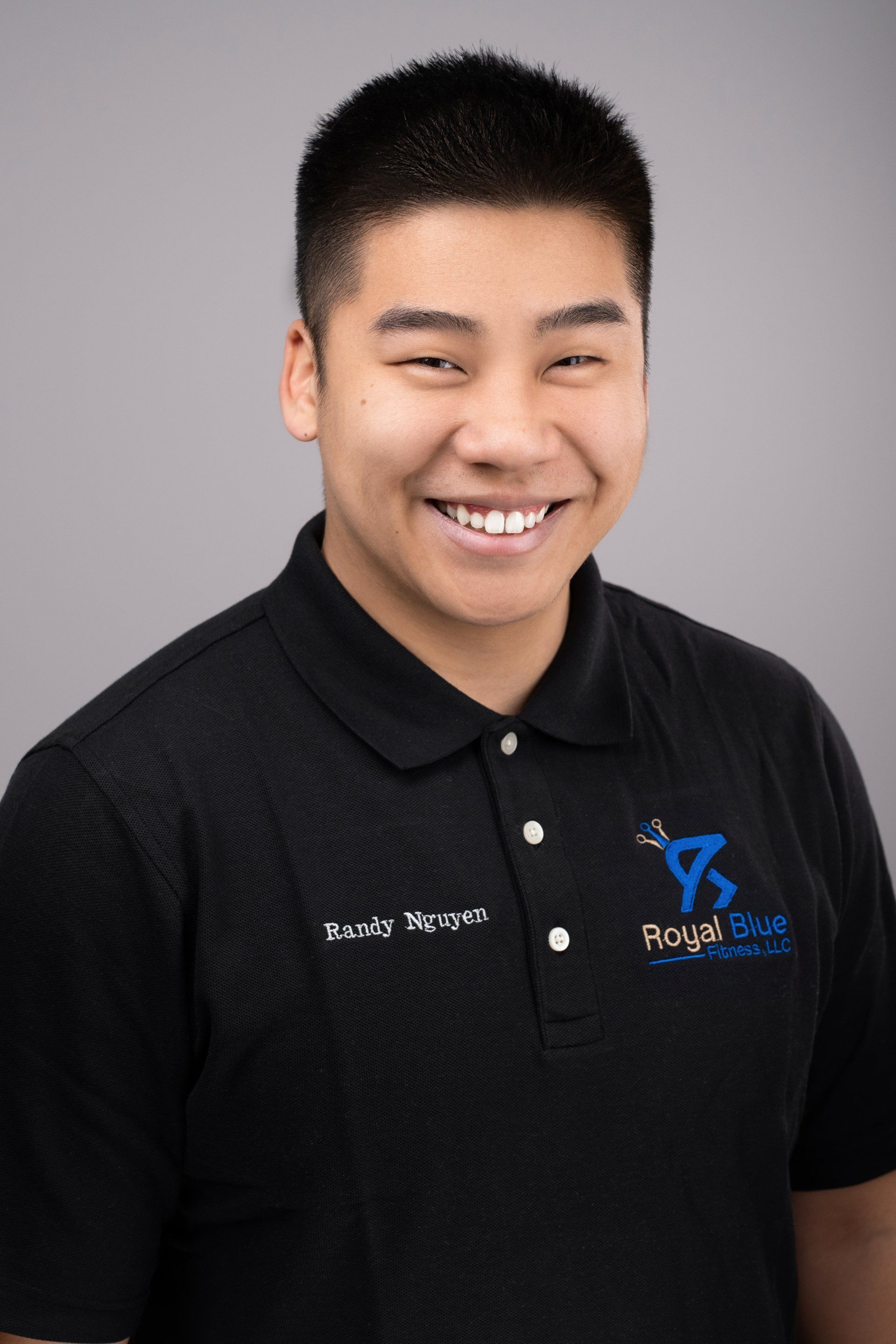 Portrait of Randy Nguyen in a black polo shirt with the Royal Blue Fitness logo, smiling confidently at the camera.