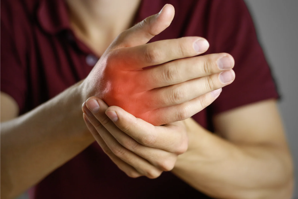 A person holding their hand with a red glowing area, indicating inflammation and arthritis in the hand.