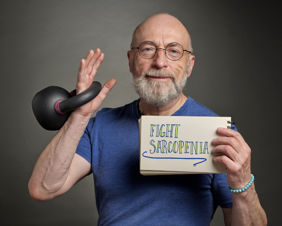 A senior man with glasses and a beard, lifting a kettlebell while holding a sign that reads 'Fight Sarcopenia', symbolizing strength against age-related muscle loss.