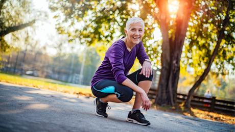 Strong for Life: health-smart training for energy, bone strength, and healthy aging. Smiling active woman in athletic wear kneeling in a sunny park after a workout.