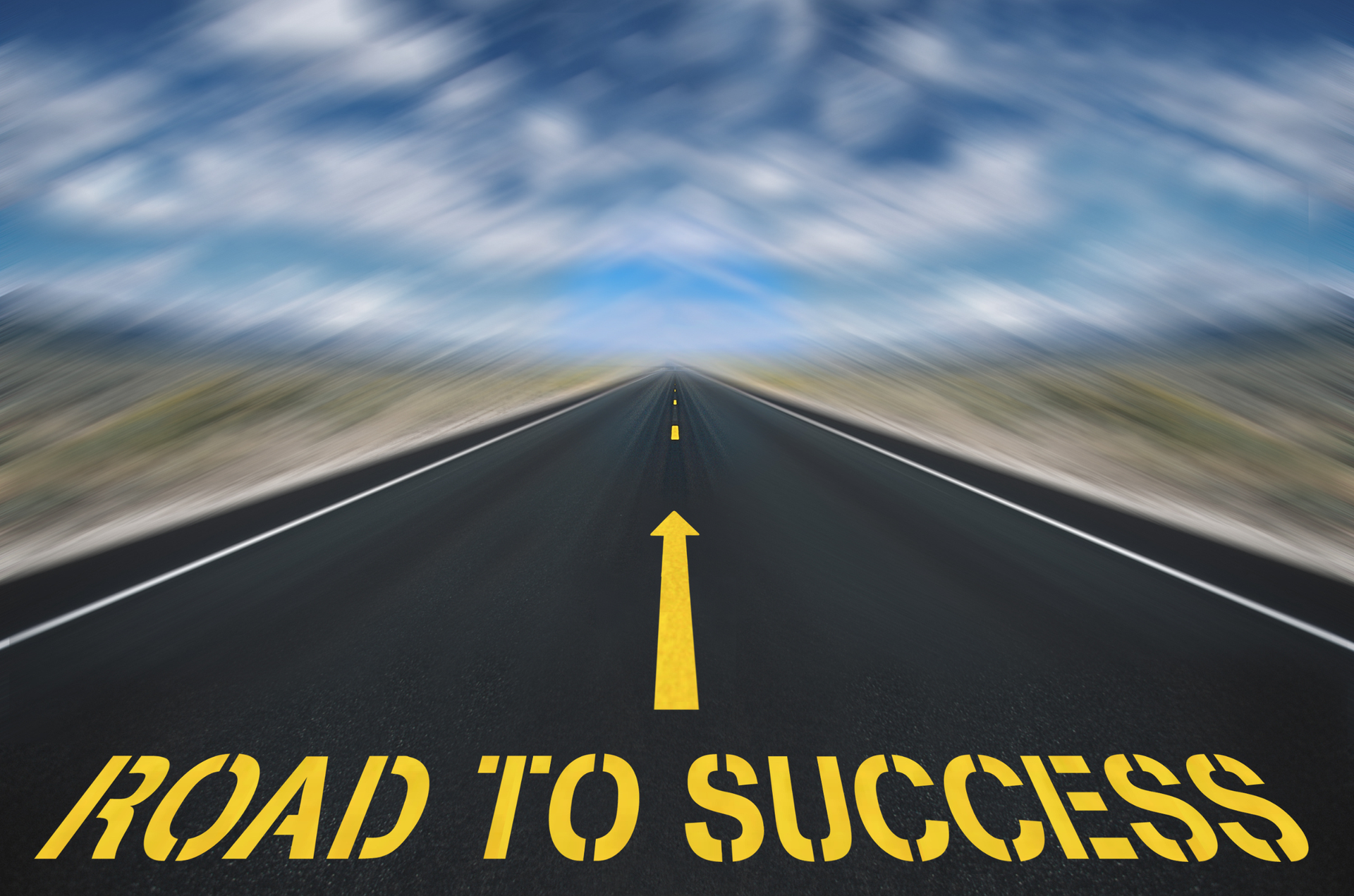 Open highway with ‘ROAD TO SUCCESS’ painted on asphalt and an arrow pointing forward.