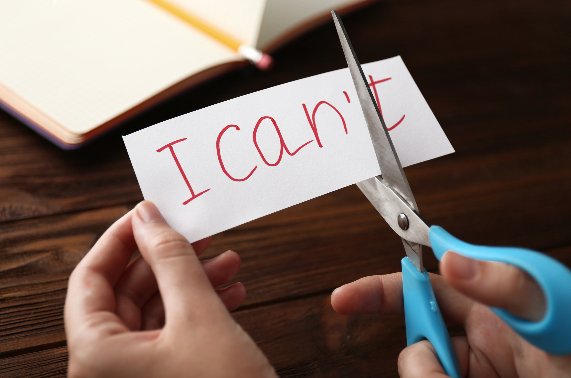 Hands cutting a paper that says ‘I can’t,’ leaving ‘I can.