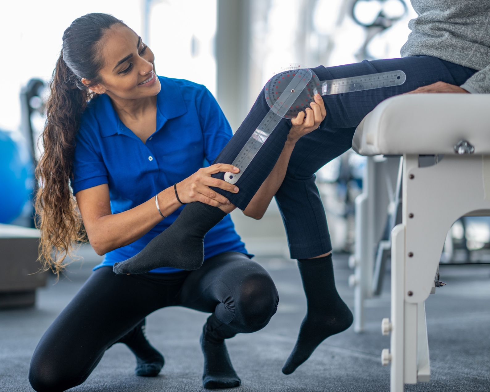 Coach measuring a client’s knee range of motion with a goniometer during an assessment.