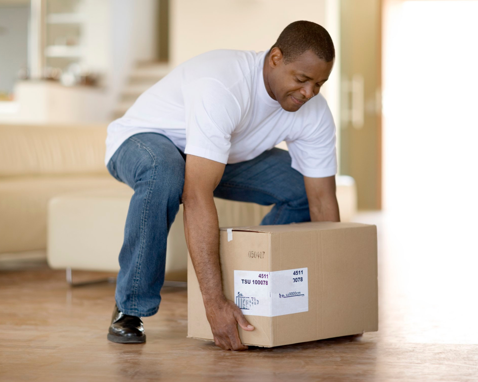 Man practicing a safe box lift at home to integrate strength into everyday tasks.