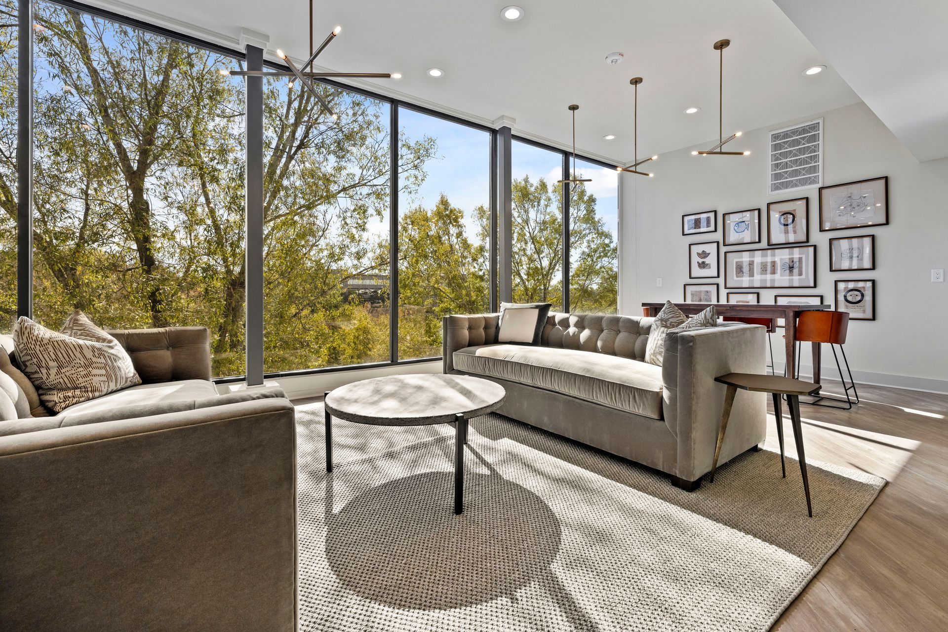 A living room with a couch, chairs, coffee table, and large windows.