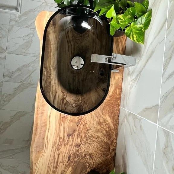 The wooden sink is placed on a wooden table in a bathroom.