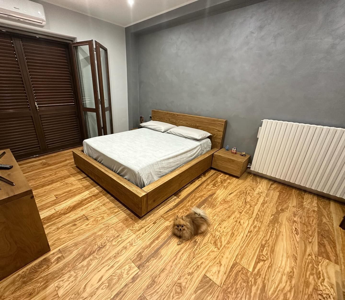 Una camera da letto con un letto, un comodino e un cane.