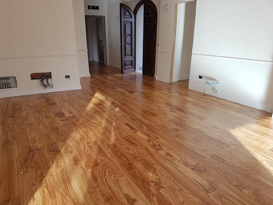 Un soggiorno con pavimento in legno e pareti bianche.