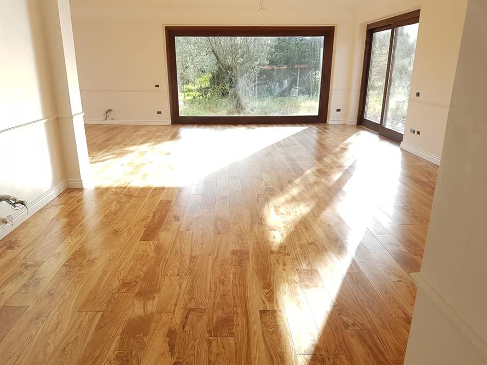Una grande stanza vuota con un pavimento in legno e una grande finestra.
