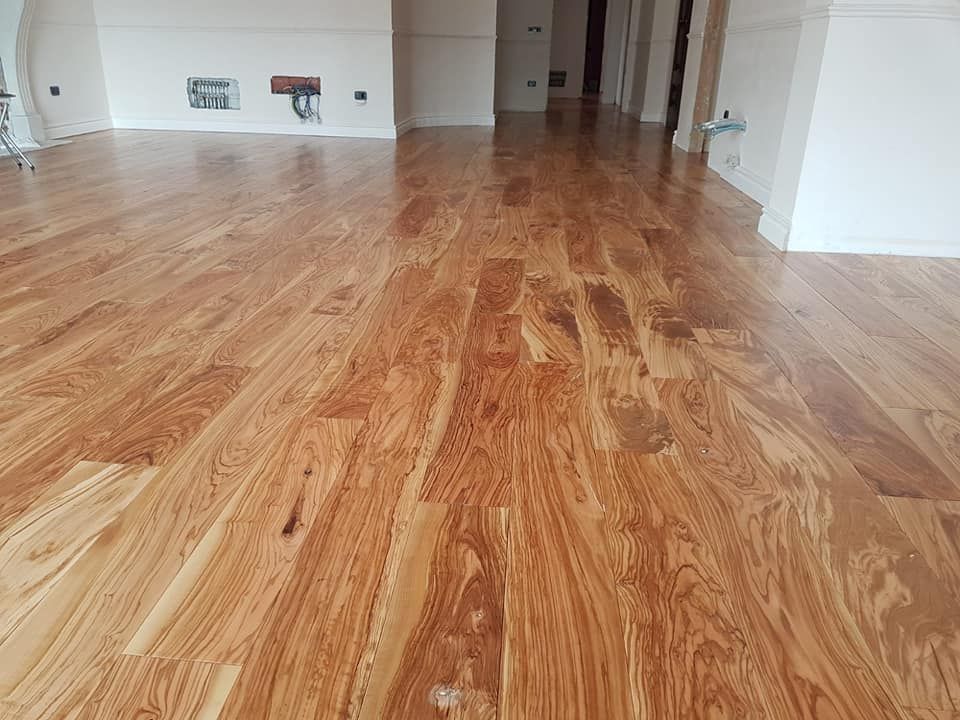 Una grande stanza con pavimento in legno e pareti bianche.