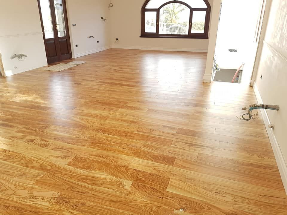 Una stanza vuota con un pavimento in legno e una finestra