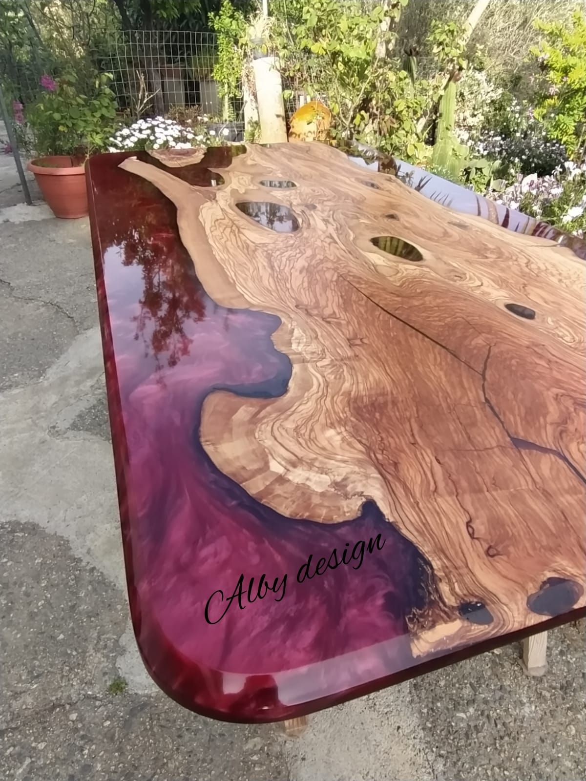 Un tavolo di legno con un piano in resina viola è appoggiato su un marciapiede.