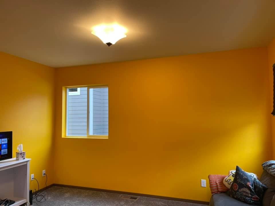 A living room with yellow walls and a window.