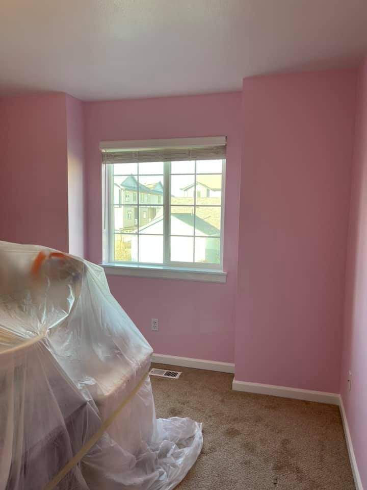 A room with pink walls and a window is being painted.