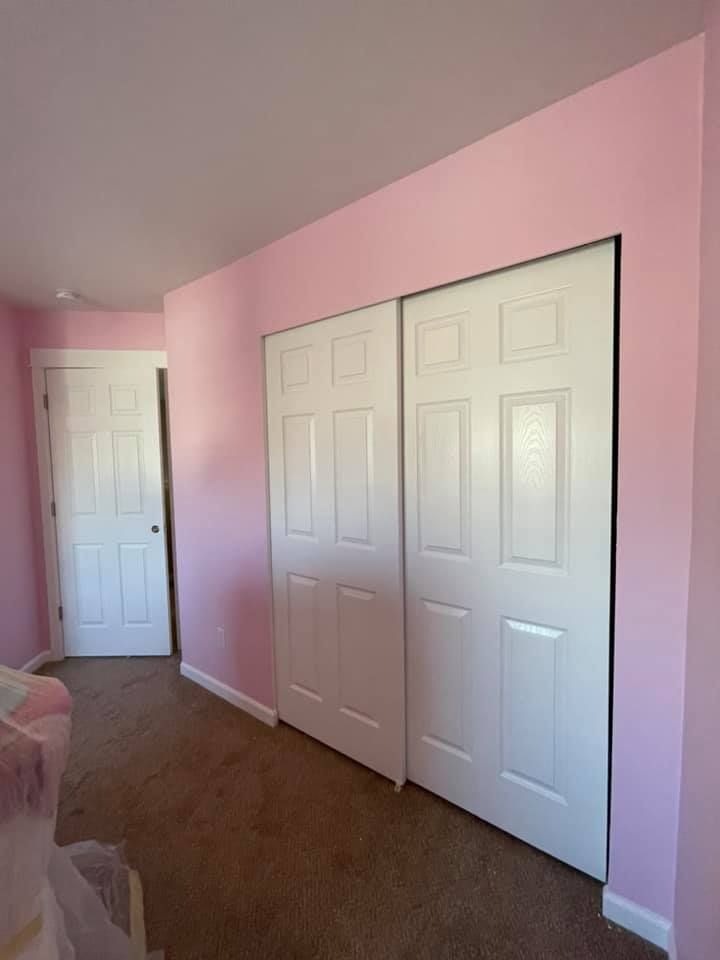 A bedroom with pink walls and white doors