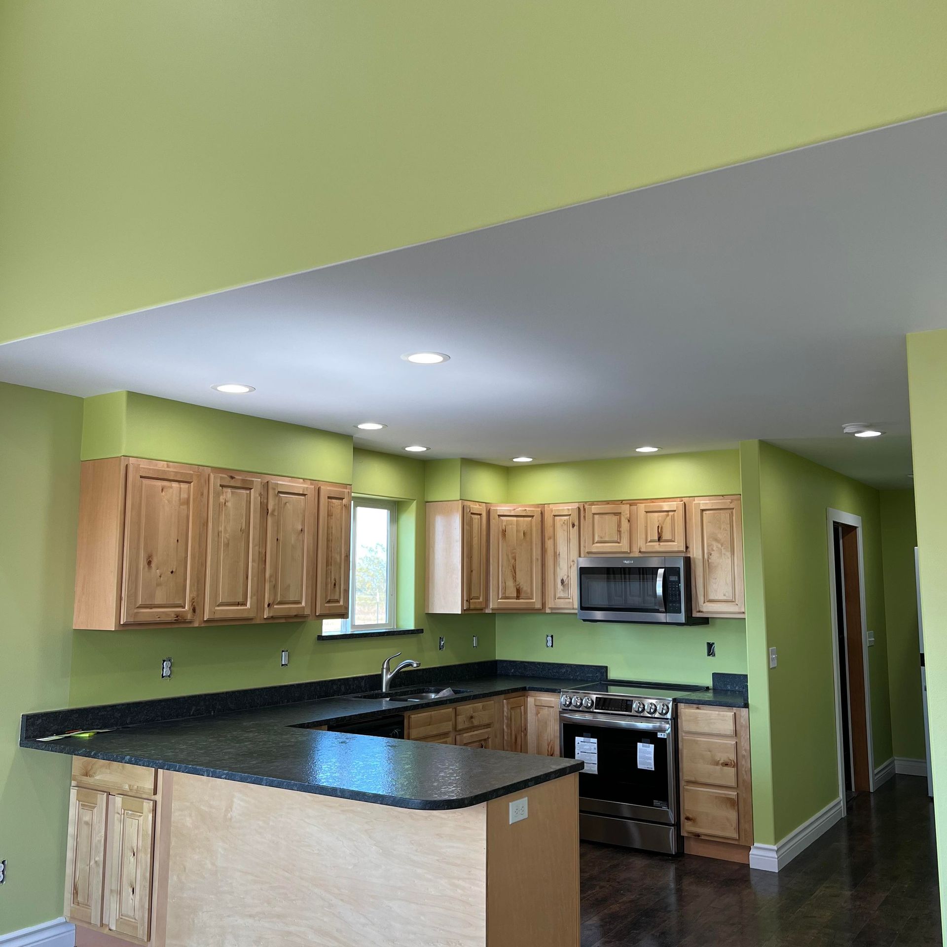 A kitchen with green walls and wooden cabinets