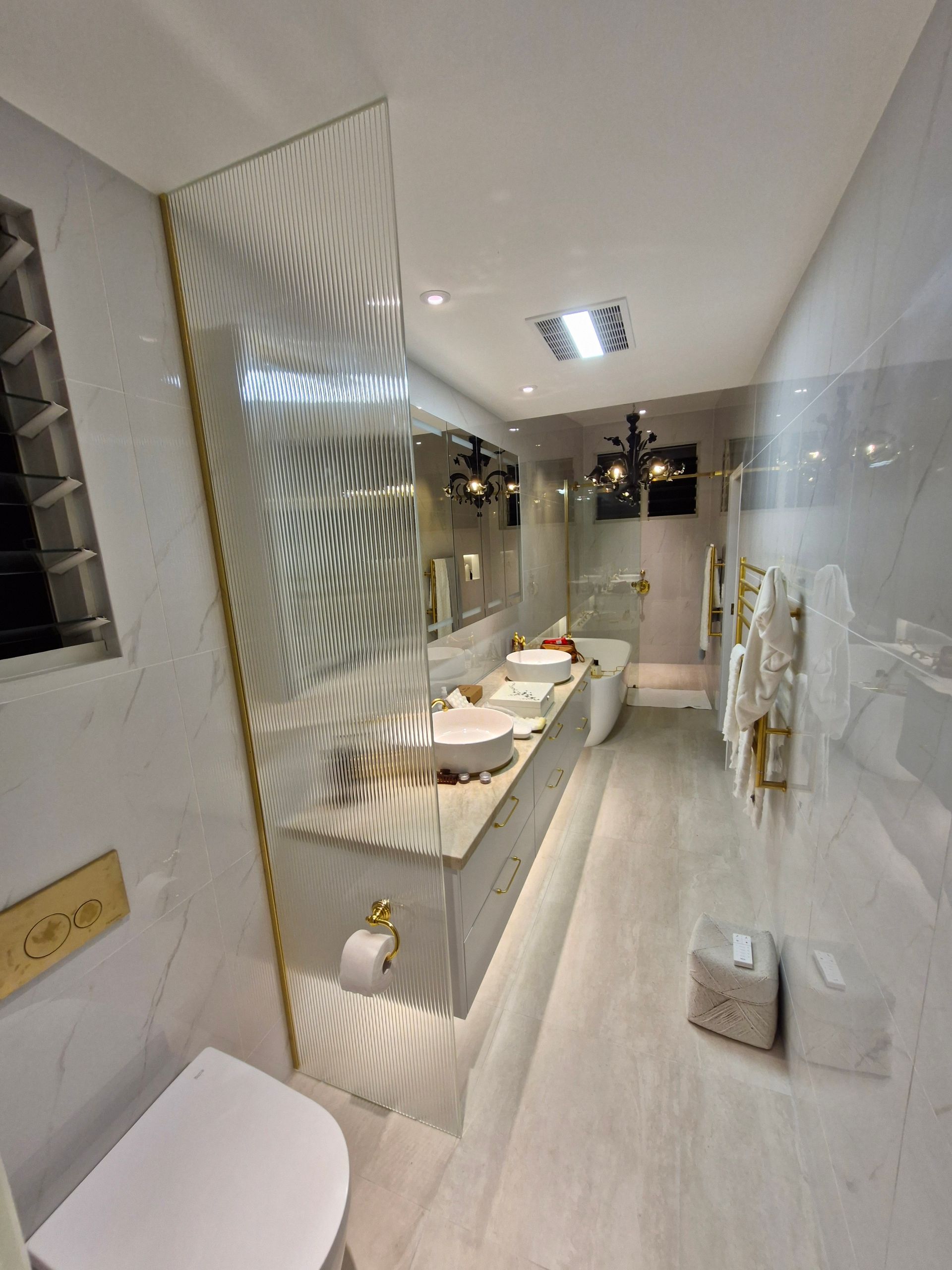 Luxurious, modern bathroom with marble, gold accents, dual sinks, and a decorative glass panel — K & J Glass in Warrell Creek, NSW