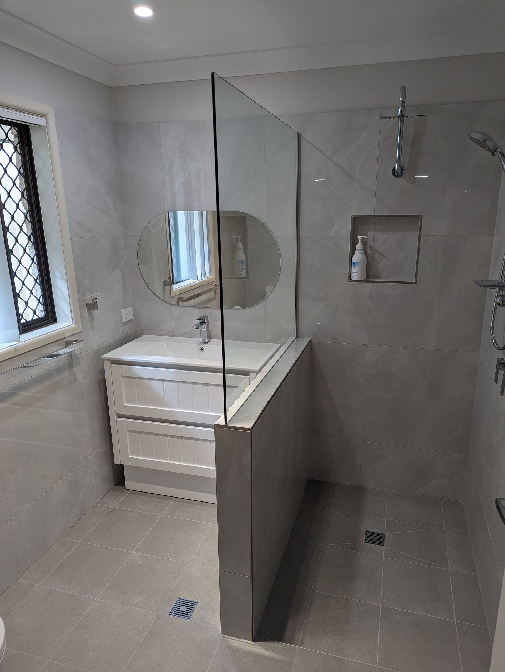 Bathroom with gray tile, shower, vanity, and large glass panel — K & J Glass in Warrell Creek, NSW