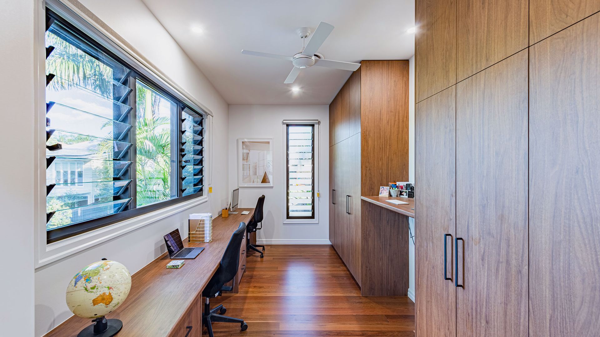 Long, narrow home office with two desks, wood cabinets, and large window — K & J Glass in Valla Beach, NSW