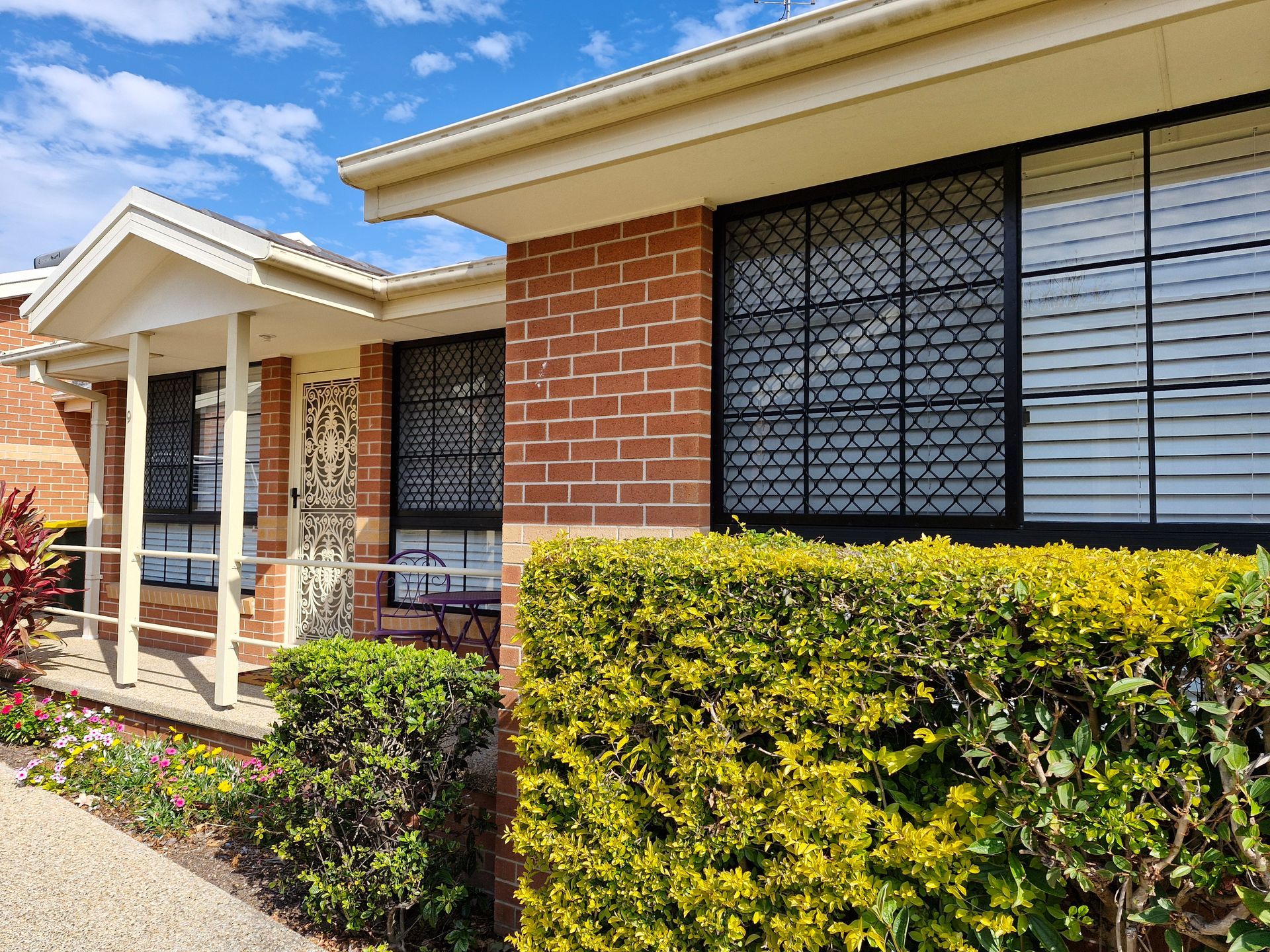 Brick home with windows, security screens, and a lush green hedge — K & J Glass in Scotts Head, NSW