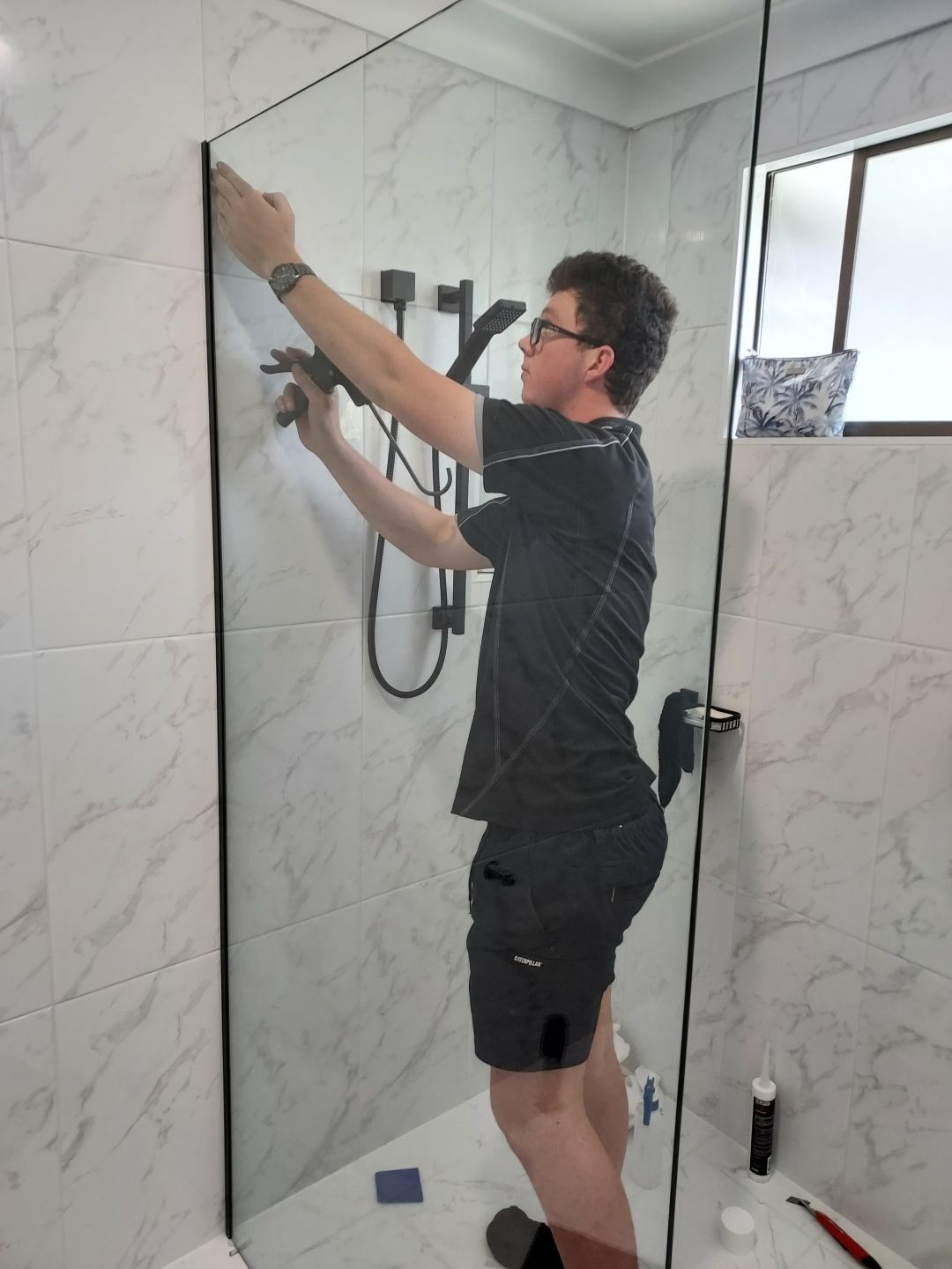 Man Installing Glass Shower Panel in a Bathroom — K & J Glass in Crescent Head, NSW