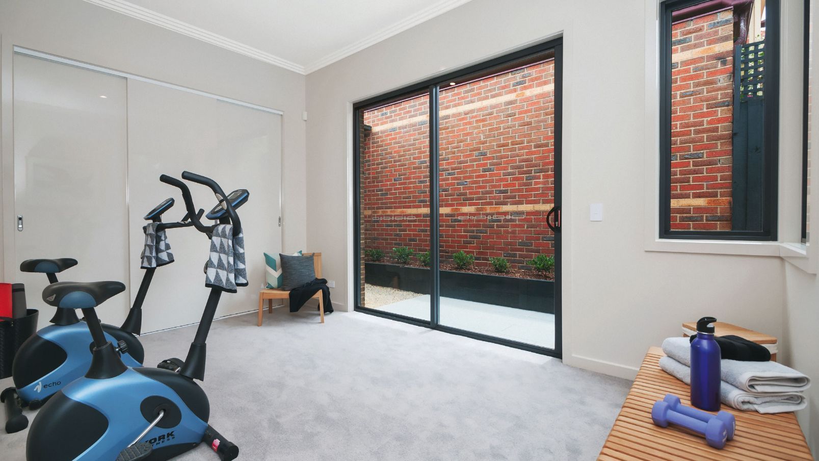 Home gym with exercise bikes, sliding glass doors, and a brick wall — K & J Glass in Bowraville, NSW