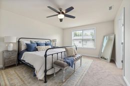 A bedroom with a ceiling fan , a bed , a bench and a mirror.